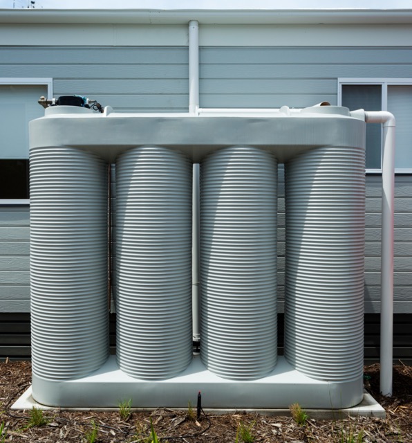 Rainwater collection tank besides a modern house for drought-tolerant landscaping