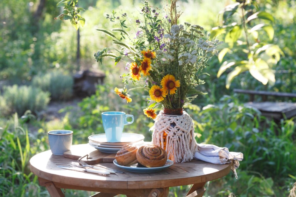 garden and tea party at the country style. still life - cinnamon rolls, cups, dishes and a vase with wildflowers