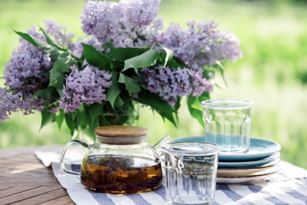 tea party in the garden. bouquet of lilacs, tea and glasses on the table